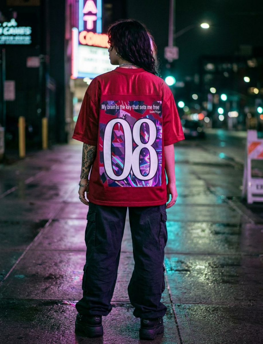 Person wearing a red shirt with a colorful design and number 08 on a city street at night.