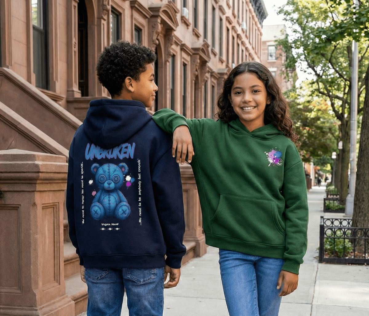 Two children wearing hoodies with colorful designs on a city street.