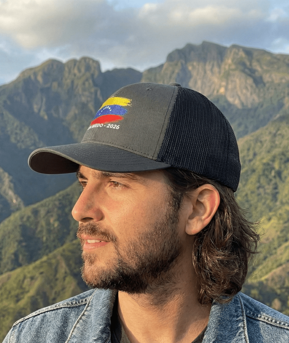 Man wearing a cap with a venezuelan flag design against a mountainous landscape