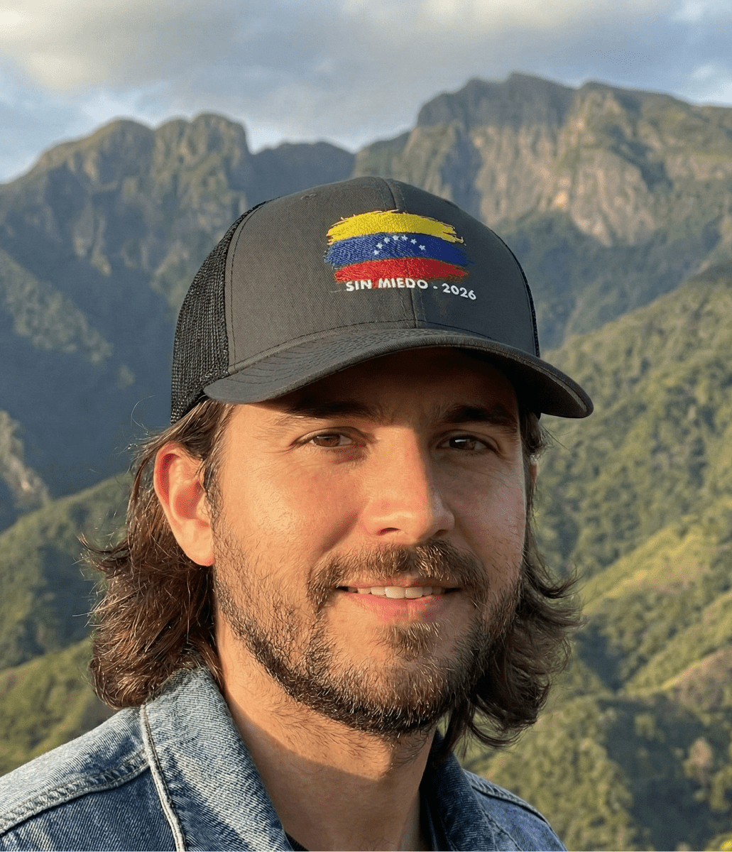 Man wearing a cap with a  venezuelan flag mountainous landscape in the background